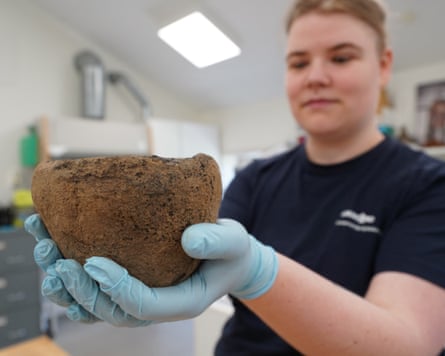 A woman in plastic gloves holding a muddy-brown coloured bowl