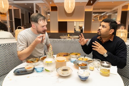 Peter and Akshat chatting and eating at a restaurant table