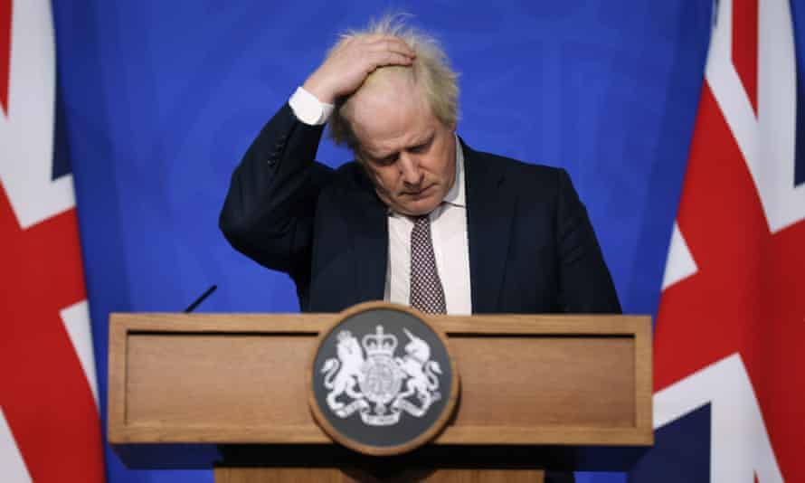 Boris Johnson avec la main sur la tête sur le podium