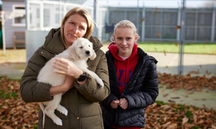 One of Willow’s puppies held by its new owner, who is standing next to her daughter.