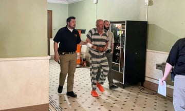 a man in handcuffs is escorted through a courthouse