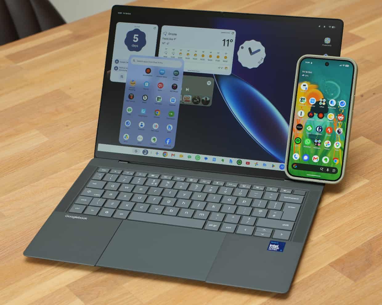 A Google Pixel 11 Pro phone leaning on an Asus Googlebook 14’s screen.
