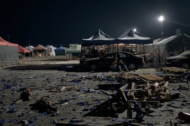 One man comforts another near the body of a third man under the night sky