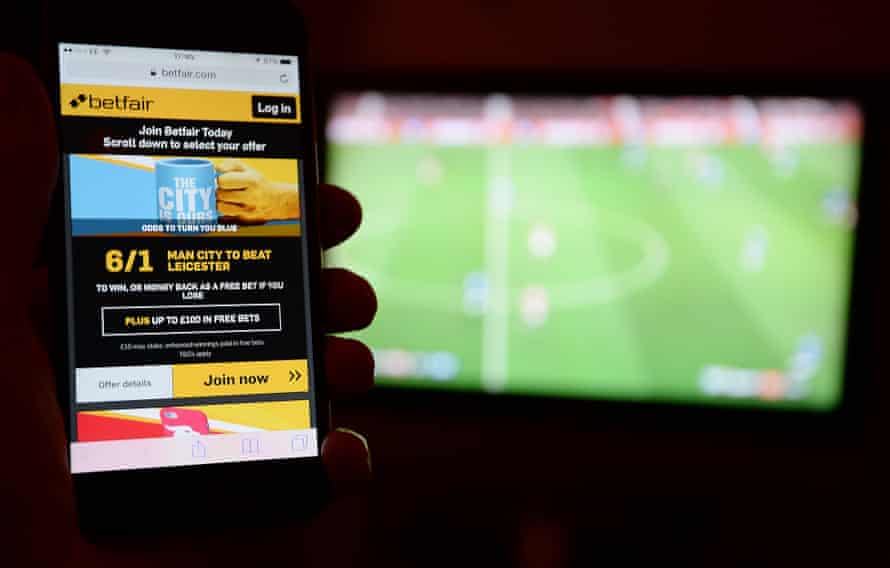 Betfair on phone in front of TV showing football