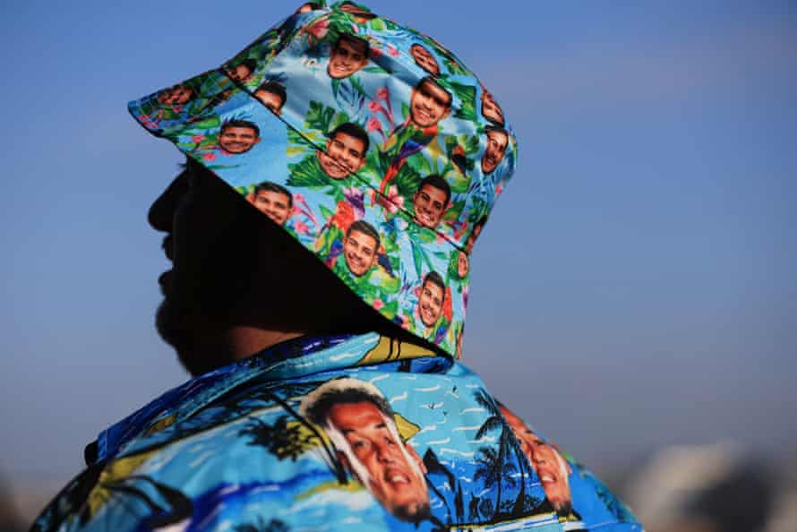 A Newcastle United fan is seen wearing a shirt featuring Newcastle United's Joelinton and a Bruno Guimaraes hat outside the stadium.