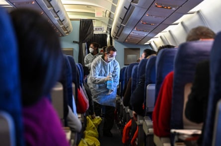 A crew member of an evacuation flight of French citizens from Wuhan gives passengers disinfectant during the flight to France on February 1, 2020, as they are repatriated from the coronavirus hot zone