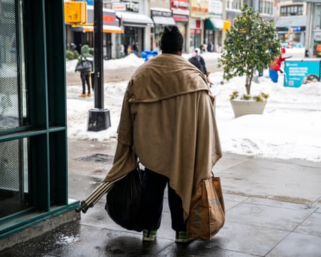 a man wrapped in a blanket holds bags