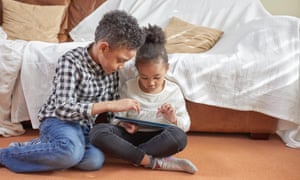 Two children (models) using a tablet device