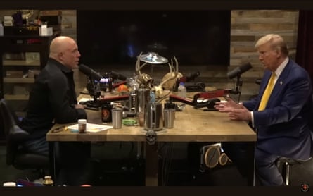 Joe Rogan and Donald Trump sitting at a table talking into microphones