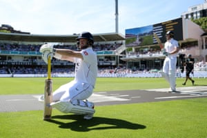 A batsman in cricket whites and pads leans on his bat as he crouches