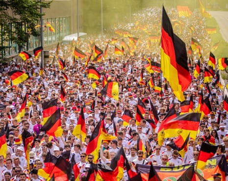 German fans wave their national flag as they march through the streets of Stuttgart towards the stadium to watch the Euro 2024 quarter-final against Spain.