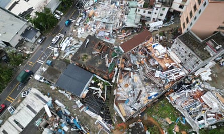 Overview view of buildings shattered and broken apart, with vans and cars on the street, after a tornado in China