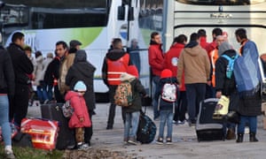 Migrants wait to board buses to leave the Calais camp