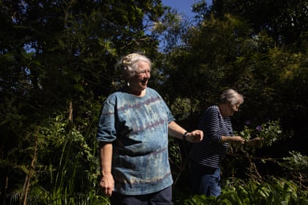 Two women standing in a lush green garden looking at plants