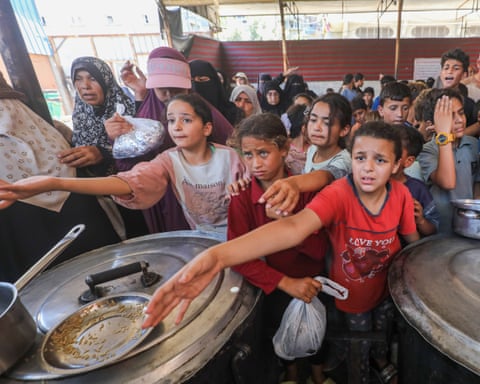 Worried looking children in crowd with hands outstretched