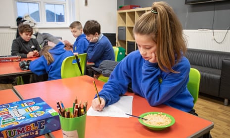 Pupil Hall Storm draws and eats breakfast, while other pupils behind play games and eat breakfast, at Cadoxton Primary School in Barry, South Wales, one of the schools taking part in the trial.