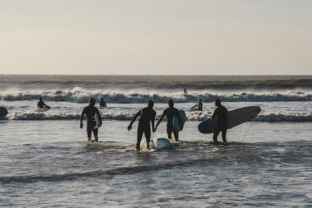 Surfers wade into the sea.