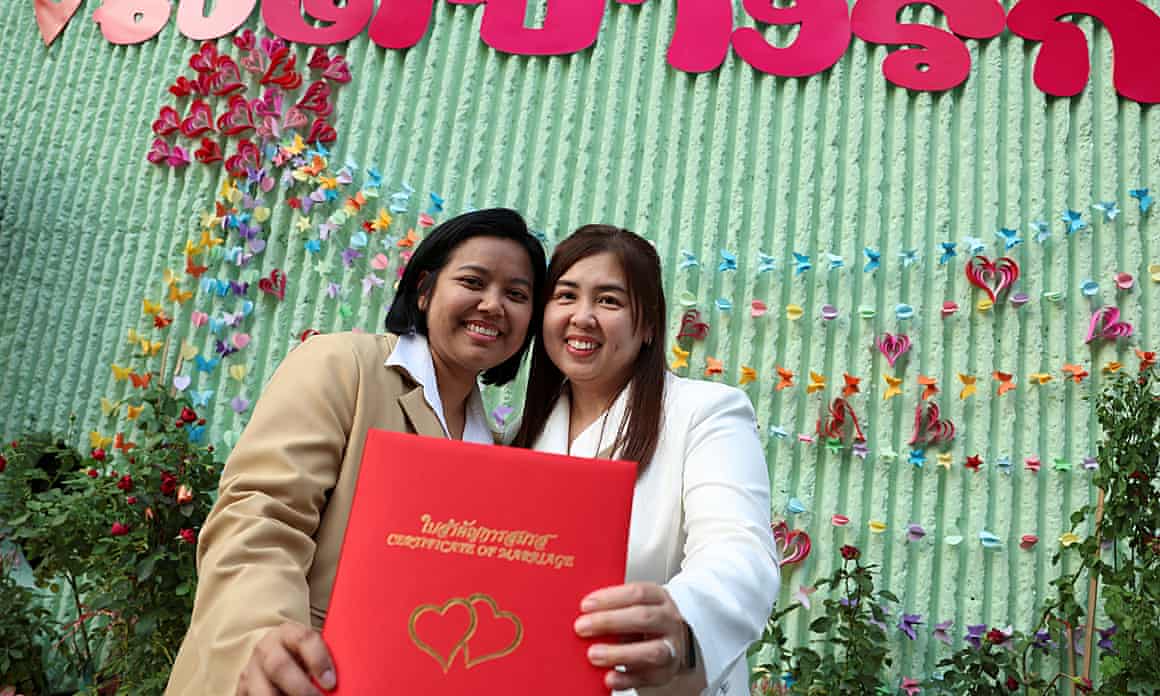 Two smiling women holding red document