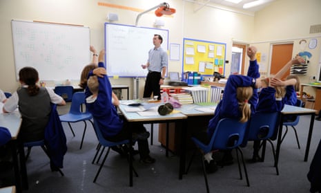 Primary school pupils working in classroom with male teacher