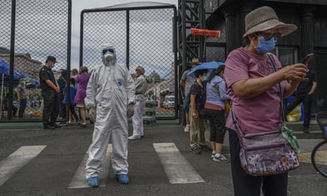 An epidemic control worker directs people at a coronavirus testing station in Beijing, China, as authorities tackle the most significant outbreak in the country since February.