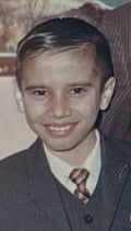 A young Avtar wearing a three-piece suit and tie, grinning at the camera