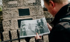 Man holds up an old photograph next to the Mayflower Pilgrims Memorial in Southampton