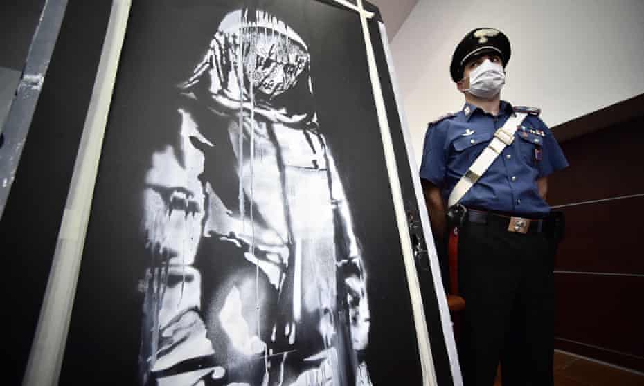 A policeman, pictured in 2020, stands guard near a piece of art attributed to Banksy, that was stolen at the Bataclan in Paris in 2019.
