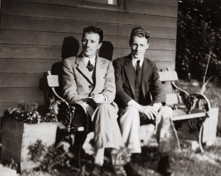 Dressed in suits, Walter Smith and Arthur Fitzsimmons sit on a bench before a wooden building