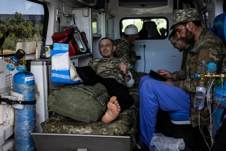 Yevhen Udovyehenko (left) and Ruslan Tymchuk (centre in glasses) sit in an ambulance in Pokrovsk after being injured and evacuated from the frontline.