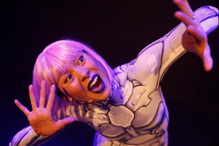 A woman with pink hair in a skeleton body suit gesticulating with her hands