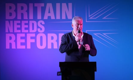 Lee Anderson standing behind a podium with a microphone
