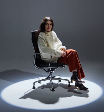 Sirin Kale in a leather chair with a spotlight on her
