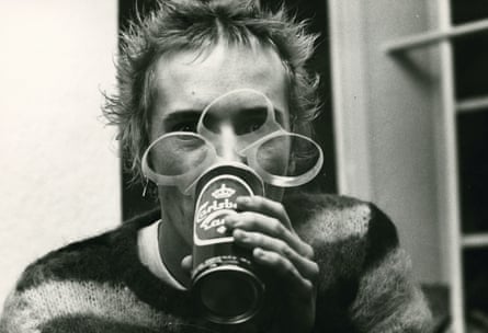 A man wearing a stripy jumper holding a can of lager in front of his face