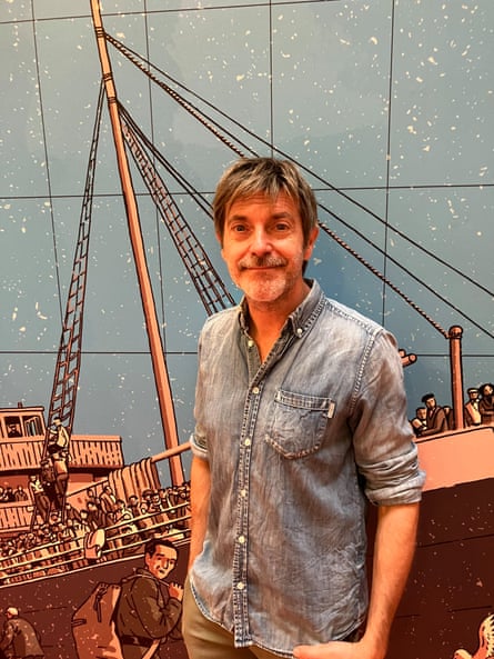 a man in a blue shirt in front of an illustration of a boat