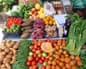 A stall piled with local produce including potatoes, green. beans, tomatoes, pumpkin, types of sweet potato and fruit.
