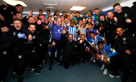 Huddersfield Town head coach Neil Warnock celebrates avoiding relegation with his players in May