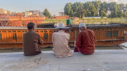Elderly men sitting by a river in Srinagar