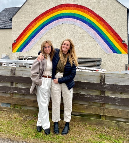 Amy and Laura standing in front of a mural of a rainbow