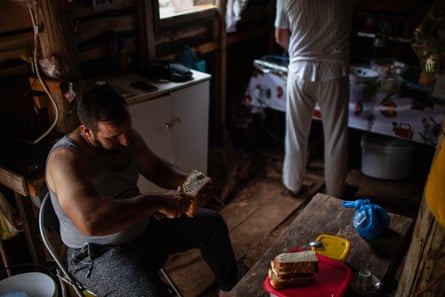 Ο Κώστας κόβει ψωμί για το μεσημεριανό γεύμα της οικογένειας μέσα στον αυτοσχέδιο καλοκαιρινό αχυρώνα τους