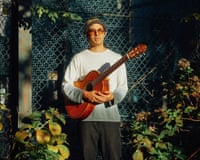 Fabiano do Nascimento standing in a garden, holding a guitar