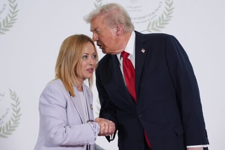 Trump and Meloni shaking hands as he says something in her ear