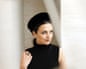 Soprano Katharina Konradi pictured in front of a beige background wearing a black pillbox hat