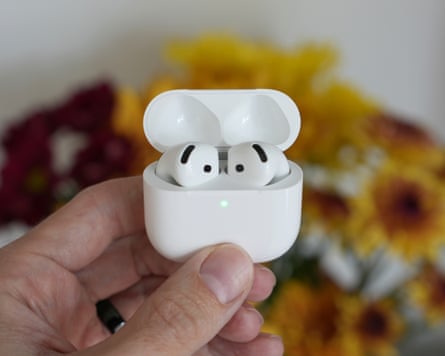 The AirPods 5 earbuds docked in their case with the lid open and held in a hand.