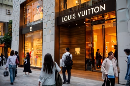 Shoppers walk past a Louis Vuitton store