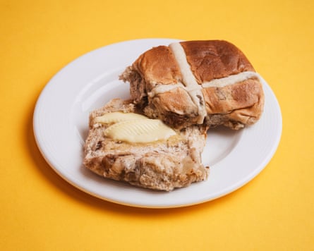 An M&S granny smith apple hot cross bun, sliced, toasted and buttered, on a white plate