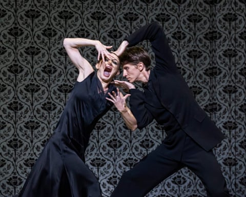 Vadim Muntagirov and Anna Rose O'Sullivan perform an expressive movement against a patterned wallpaper backdrop