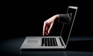 A hand reaching through a laptop to type on the keyboard