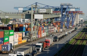 Shipping containers stacked at the Rhine-Neckar commercial port in Mannheim, Germany, 30 April 2025, as lorries drive past