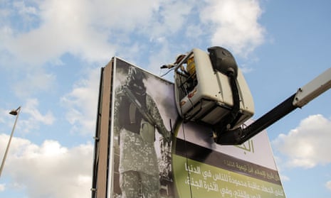 A worker is seen putting up a propaganda poster in a still from a recent Isis video