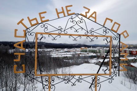 A metal installation reads ‘Happiness is not far away’ against a snow-covered landscape with buildings in the background